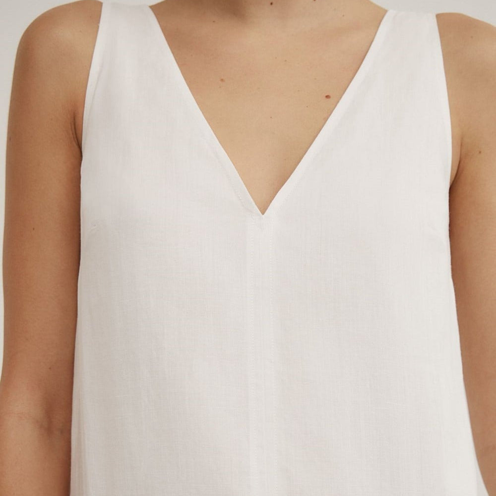 Close-up of a sleeveless white V-neck dress or romper with a loose, lightweight fabric, shown on a model.